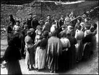 villagers gathering around a British soldier carrying a machinegun